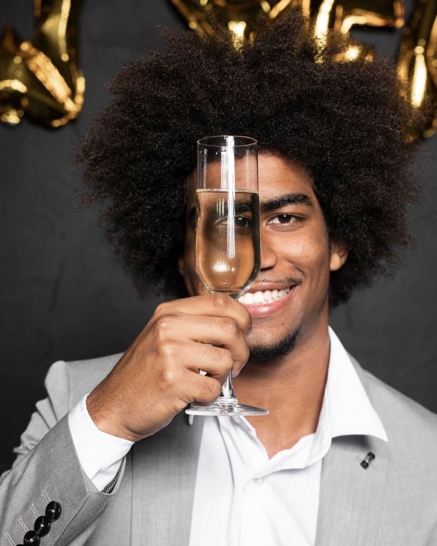 Man raising a champagne flute among gold balloons